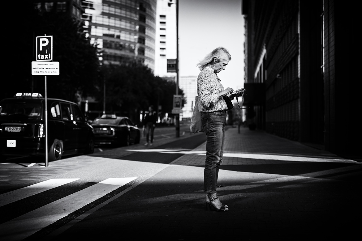 A woman checking her phone at Zuidas photographed by Friso Kooijman